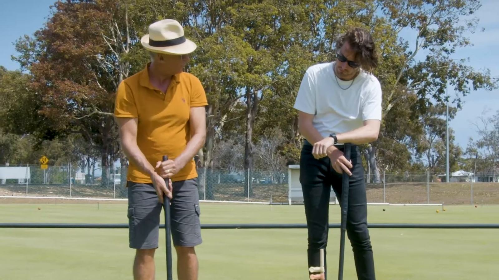 Two new players holding mallets on a sunny croquet lawn